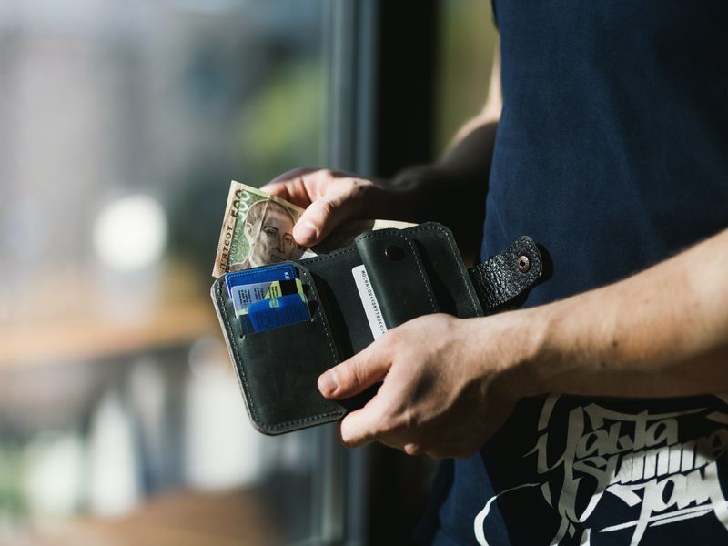 This image shows a man reaching into his black wallet.
