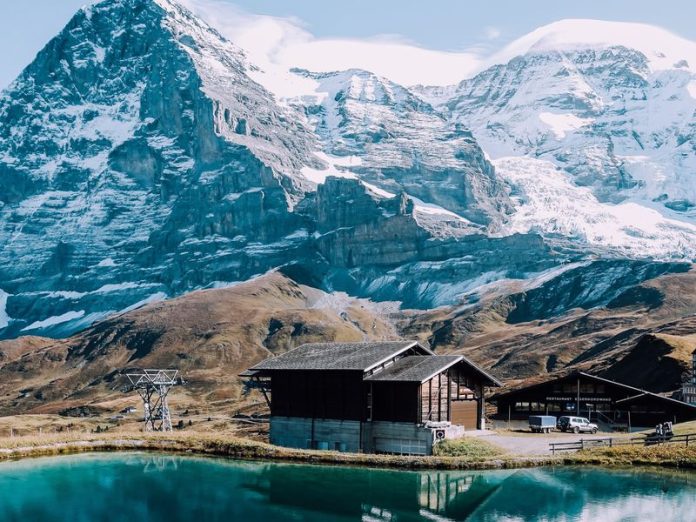 The mountains close to Geneva are some of the most beautiful in the world. This image shows a wooden chalet and lake with a mountain backdrop.