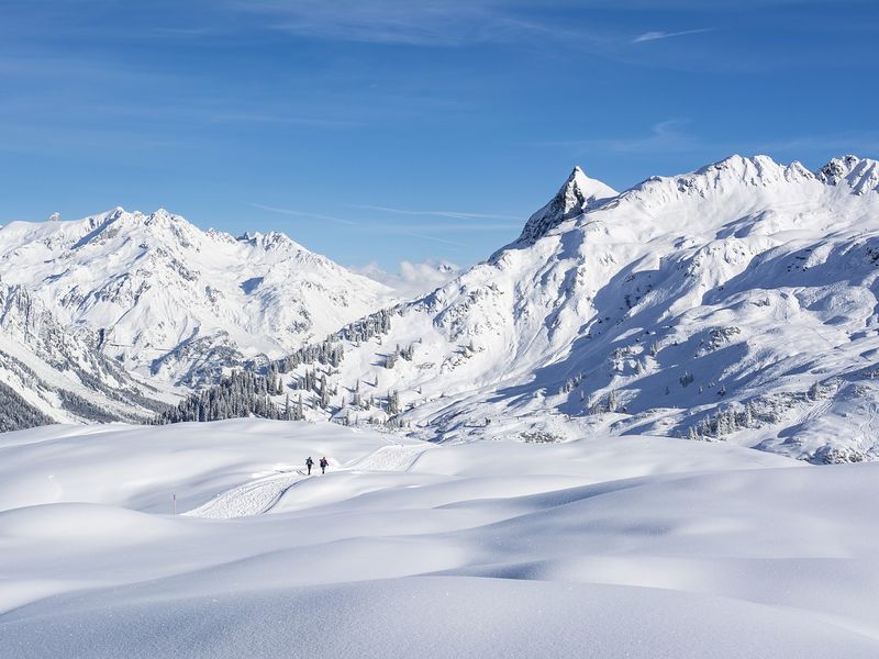 Berneuse is one of the best mountains close to Geneva. This image shows two people walking into the distance with snowy mountains.